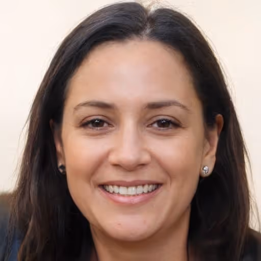 Smiling woman with long dark hair and stud earrings against a light background.