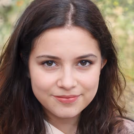 Young woman with long brown hair smiling slightly outdoors with blurred green foliage background.