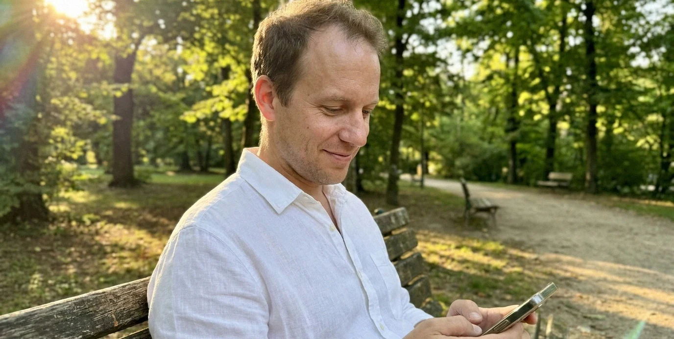 Uomo che consulta con discrezione il suo smartphone all'aperto, simboleggiando la privacy nel contatto per il trapianto di capelli.