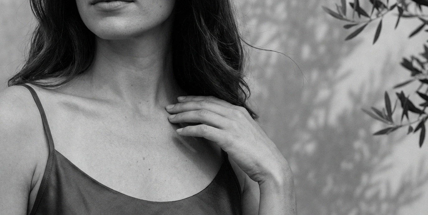 Dettaglio elegante del décolletage di una donna, simbolo di un aumento del seno naturale e sicuro.