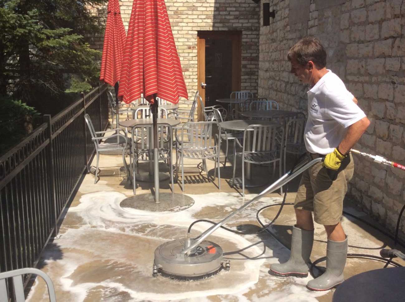Worker using line equipment for washing services in Milwaukee WI, completing a dirty driveway cleanup in just a few hours with high pressure.