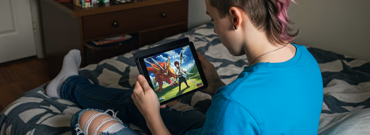 Jovem jogando anime em tablet sentado na cama.