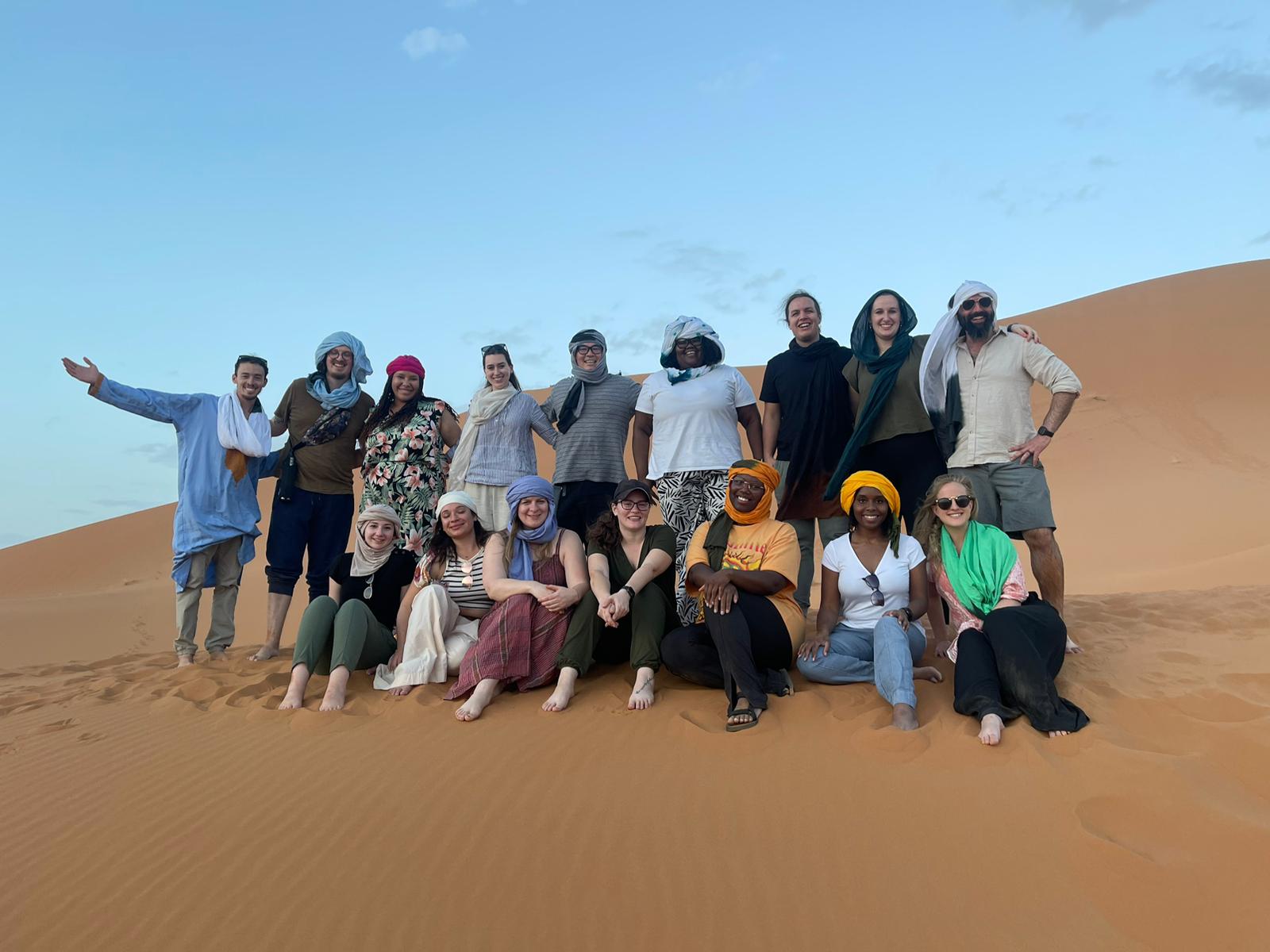 Under30Experiences travelers posing together on the Erg Chebbi sand dunes in Morocco.
