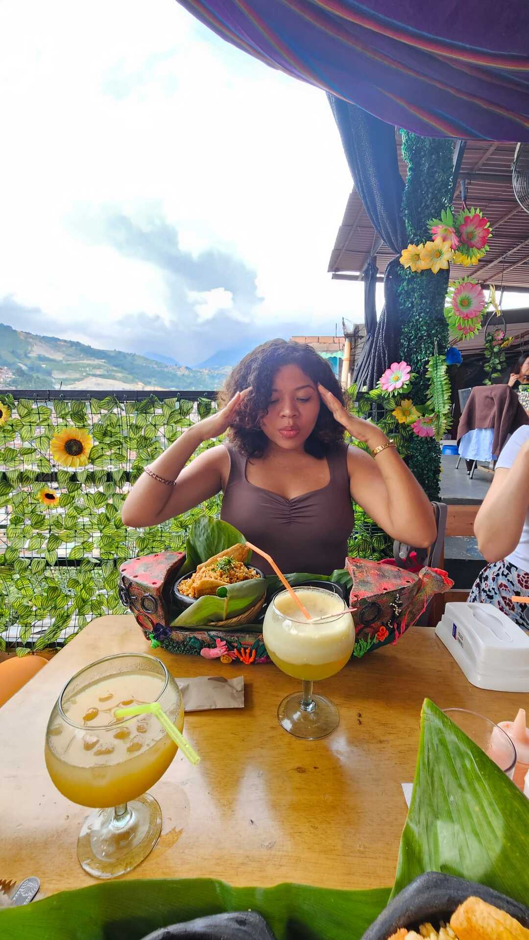 Traveler enjoying Colombian food and drinks at an outdoor restaurant with mountain views.