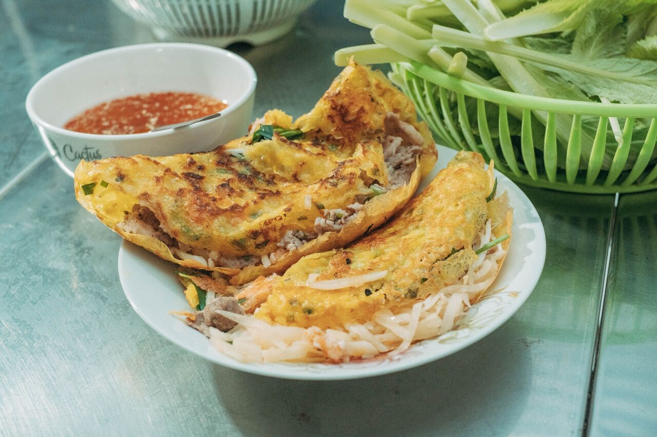 Vietnamese banh xeo crispy savory pancake served with fresh herbs and dipping sauce.