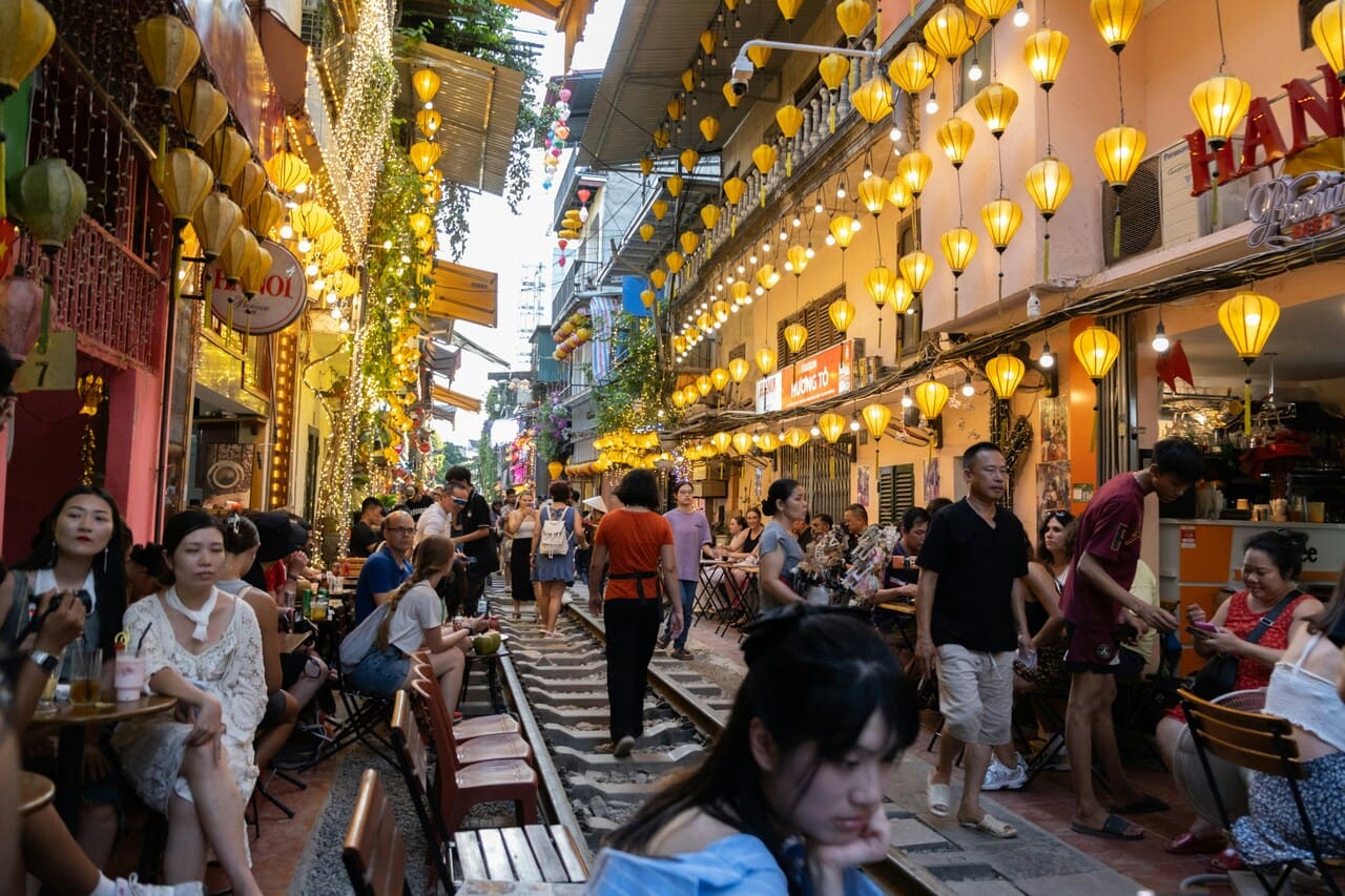 Visitors exploring Hanoi Train Street lined with lanterns, cafés, and local restaurants.