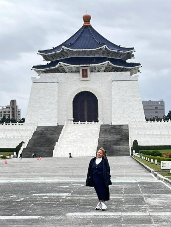 Traveler visiting Chiang Kai-shek Memorial Hall in Taipei, Taiwan, with its iconic white architecture and traditional blue pagoda-style roof.