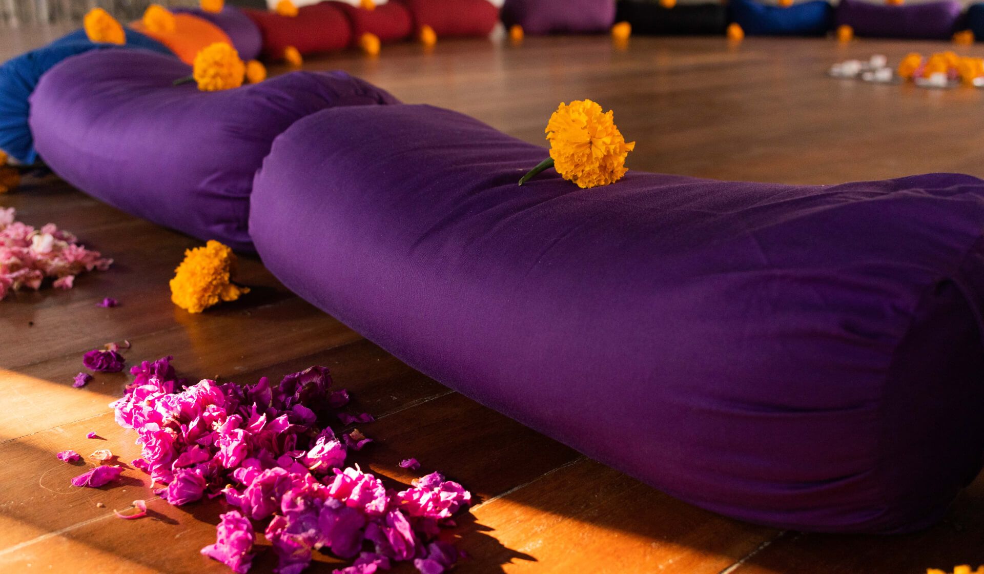 Close-up of colorful yoga bolsters arranged in a circle with flowers and candles for the closing ceremony of a 200 hour yoga teacher training