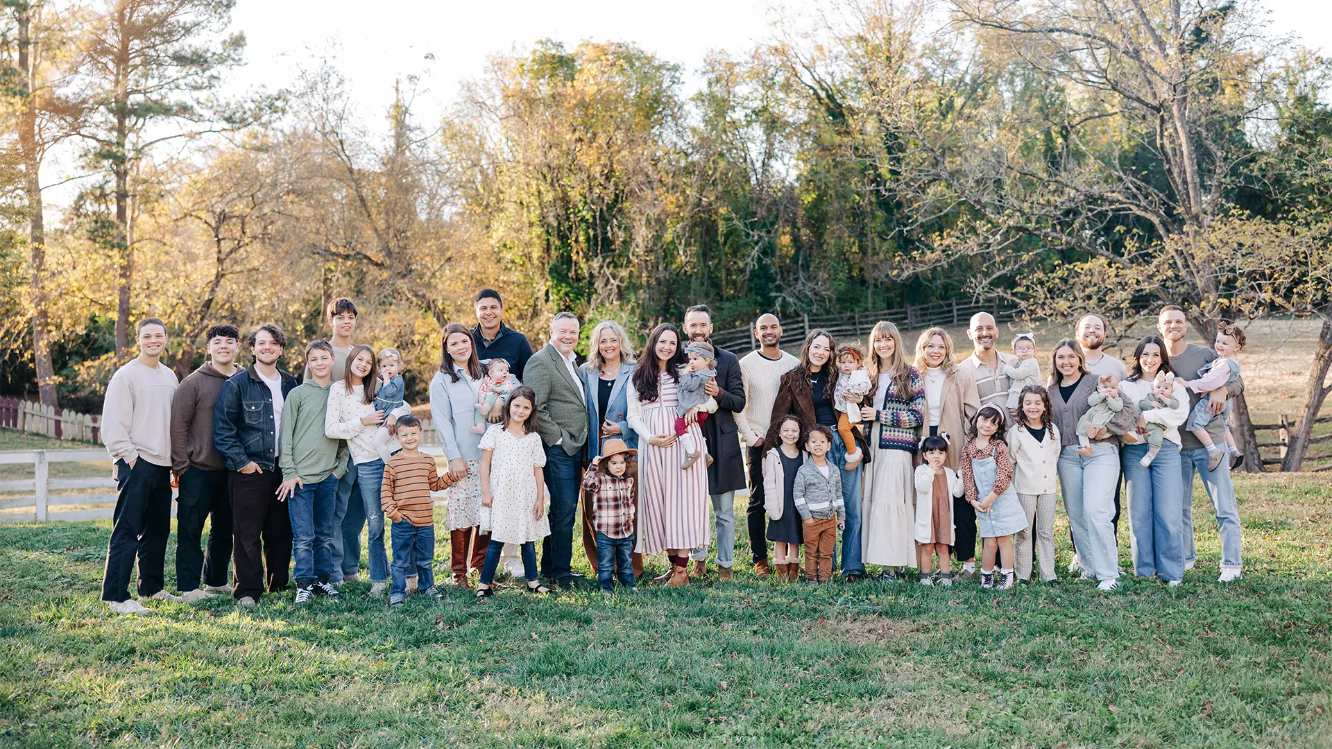 Pastor Mark and Pam Morrow with their large multigenerational family, 10 children, 6 in-laws, and over 20 grandchildren, gathered outdoors for a family portrait in 2025, smiling together in front of autumn trees