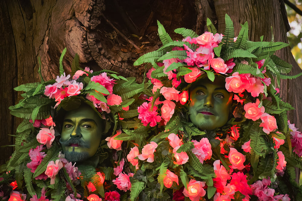 Stiltwalking trees covered in pink illuminated flowers.