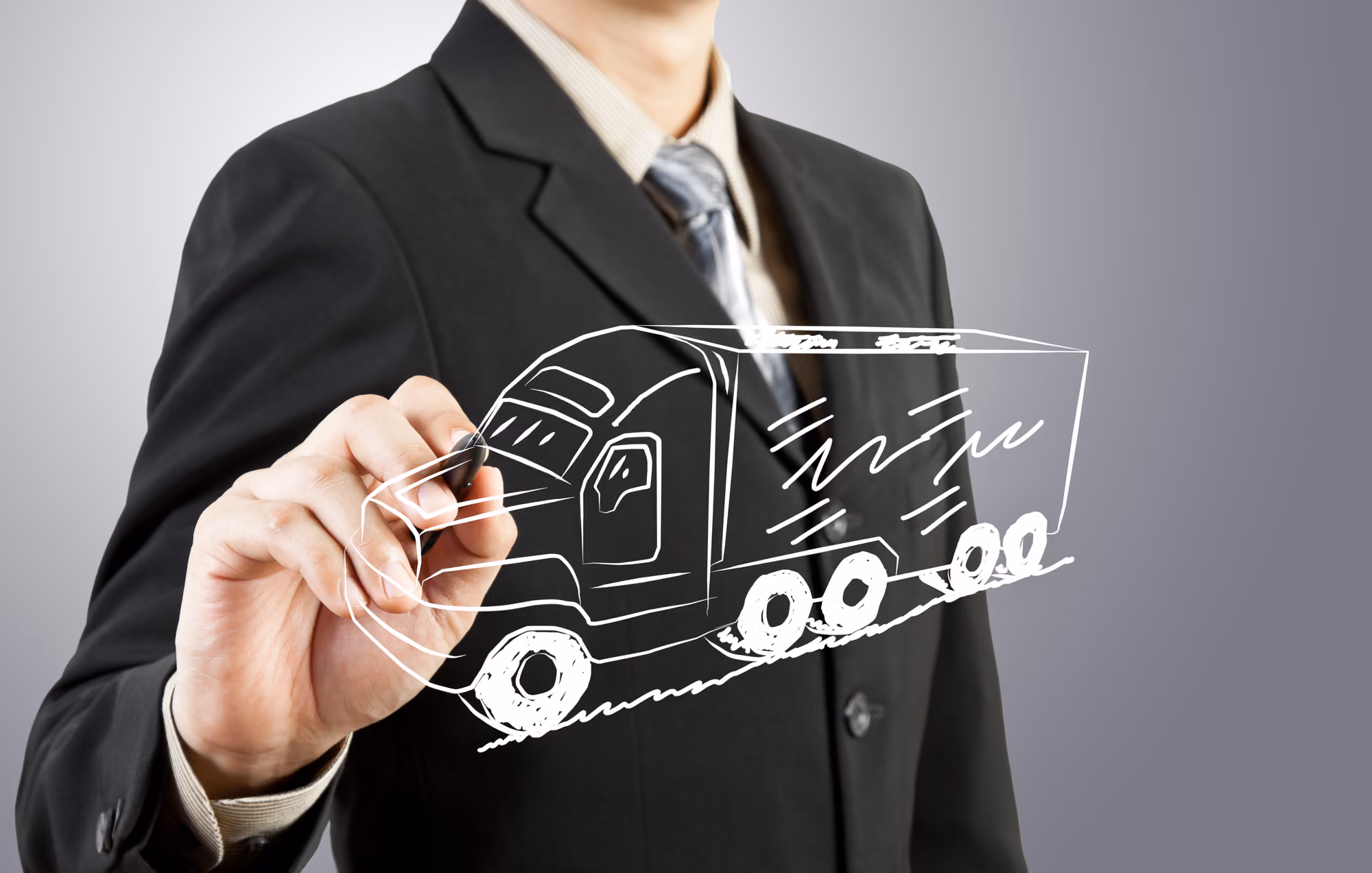 A man in a suit draws a sketch of a semi truck