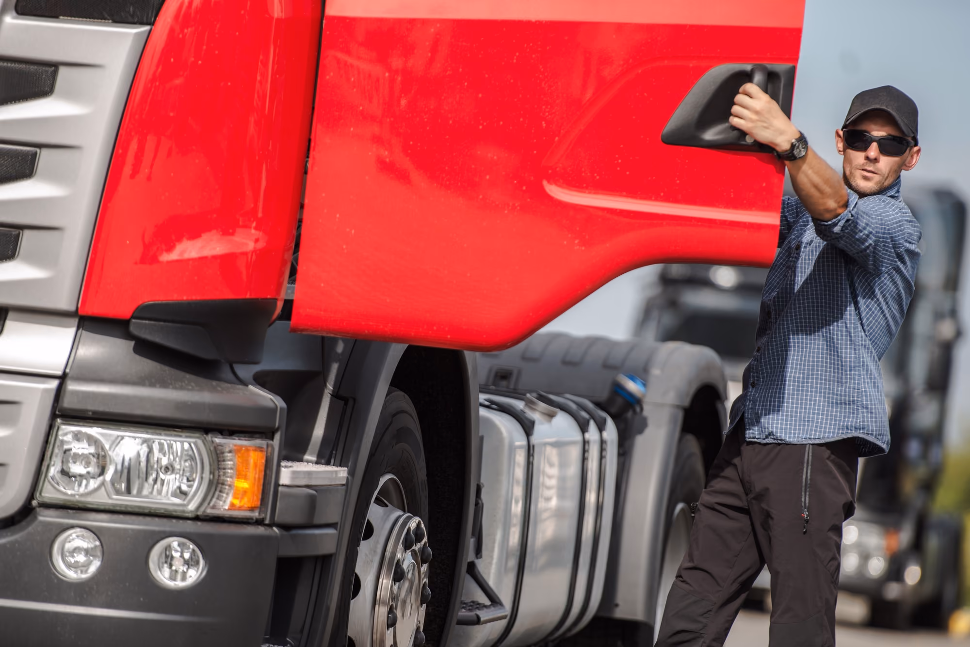 Un camionero abre la puerta de su camión rojo