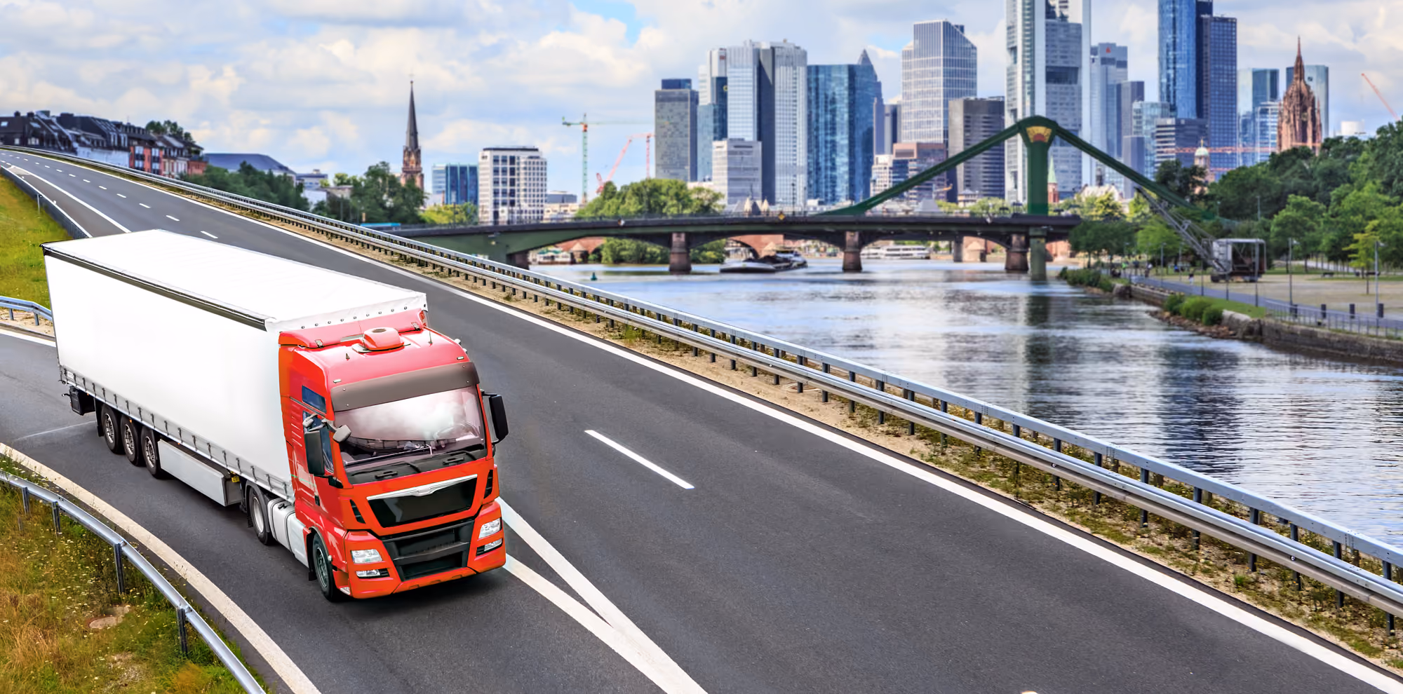 A red and white truck driving on the highway in a city
