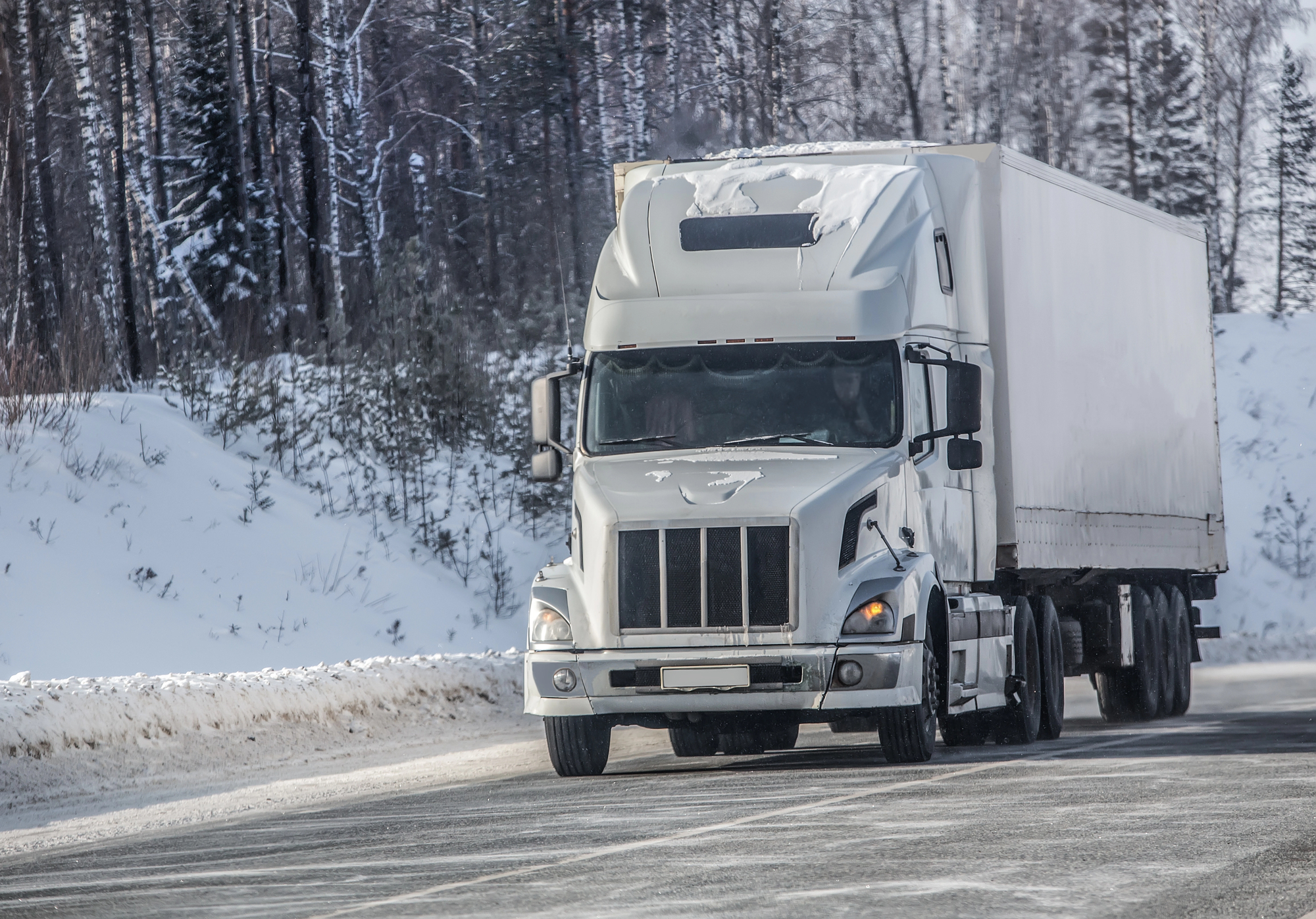 A semi truck drives on a highway in the snow