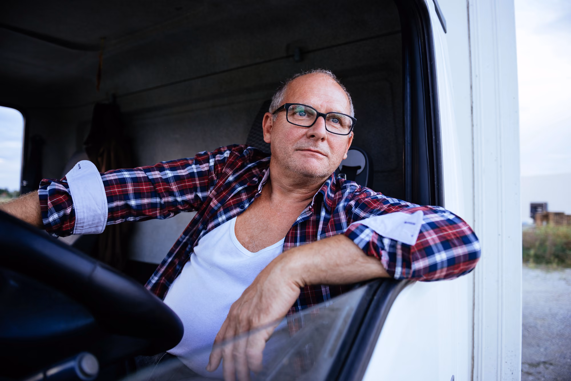 An owner operator looks out the window of his semi-truck