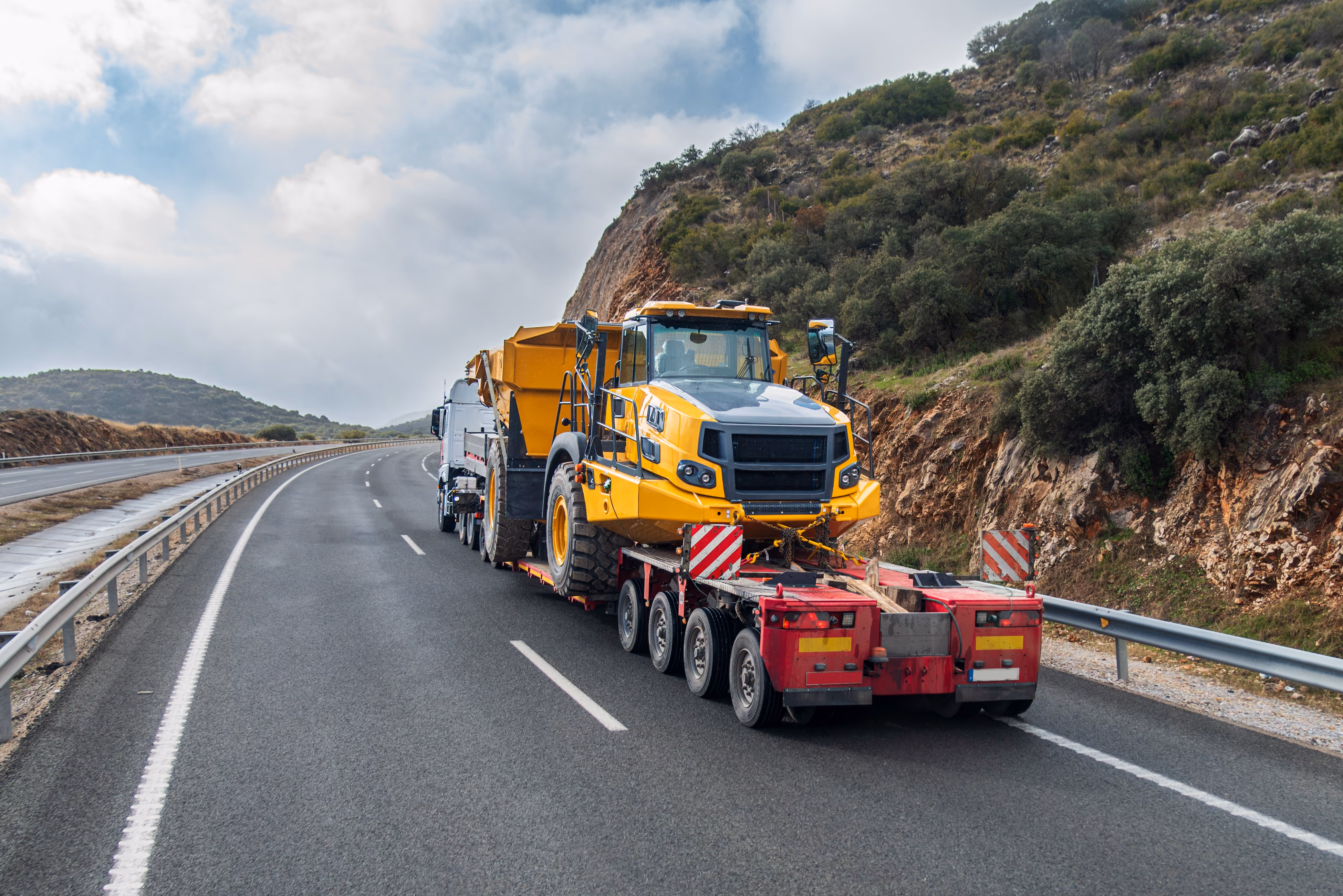 A flatbed truck hauls construction machinery