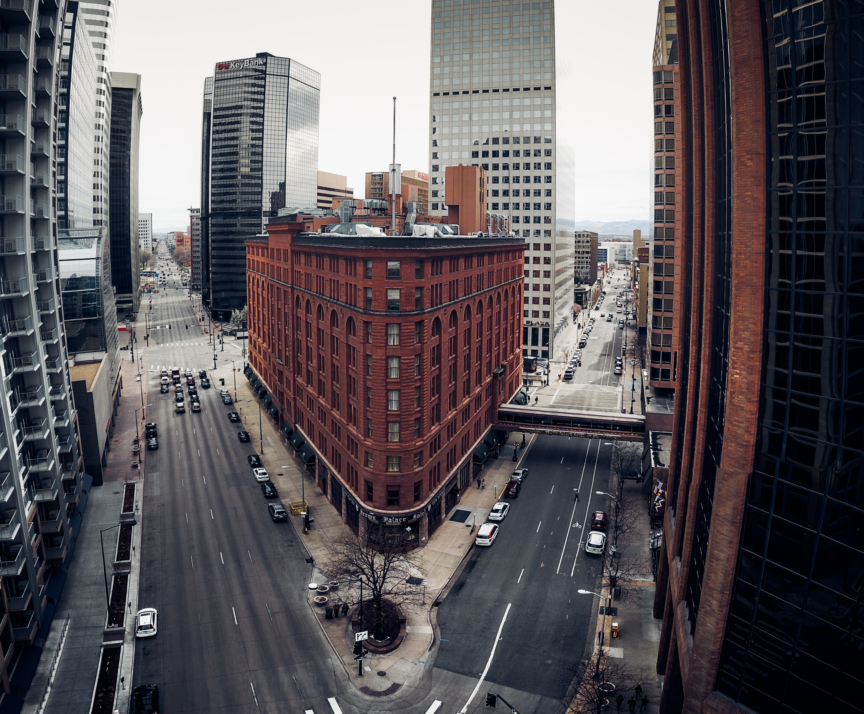 Aerial view of the historic red brick triangular Brown Palace Hotel surrounded by glass skyscrapers in downtown Denver
