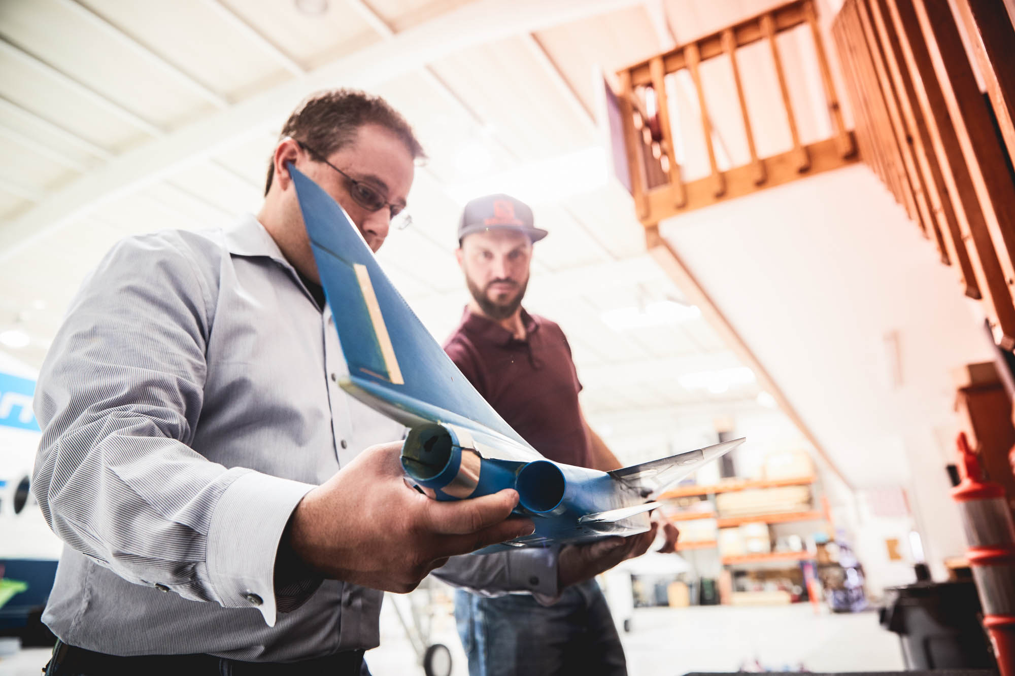 Two Boom Supersonic engineers in workshop inspecting blue scale model of the supersonic jet's tail section