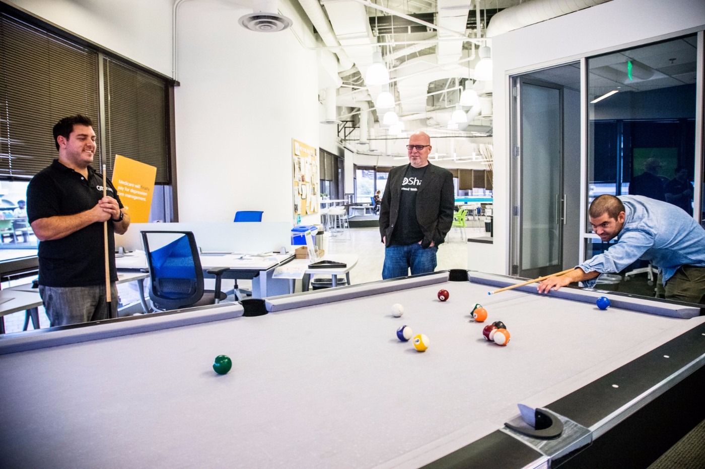 Three GoShare team members playing pool together at their San Diego office break room