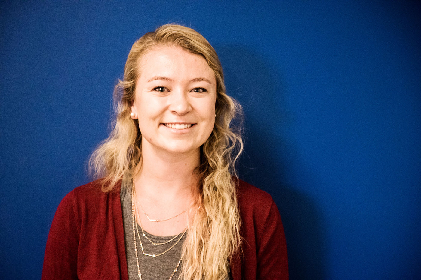 GoShare team member portrait - young woman with long blonde hair smiling against blue backdrop