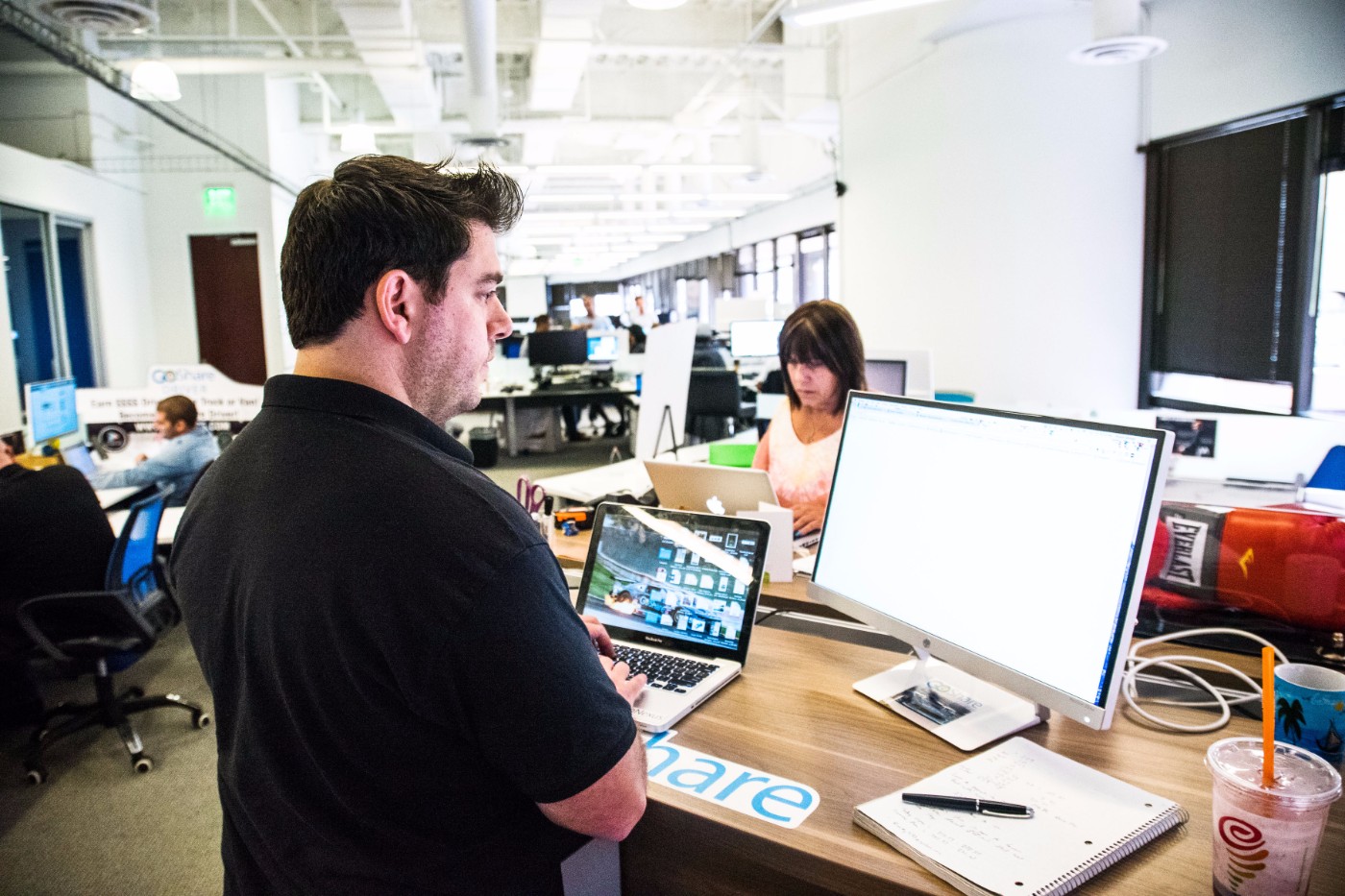 GoShare team members working at desks with laptops and monitors in their open-plan San Diego office