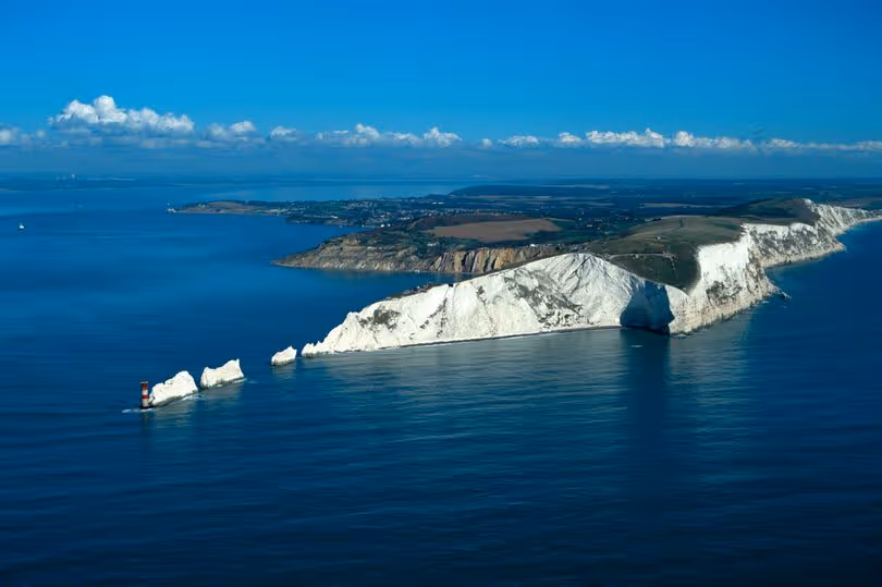 Coastal view of white chalk cliffs extending into the sea under a clear blue sky.