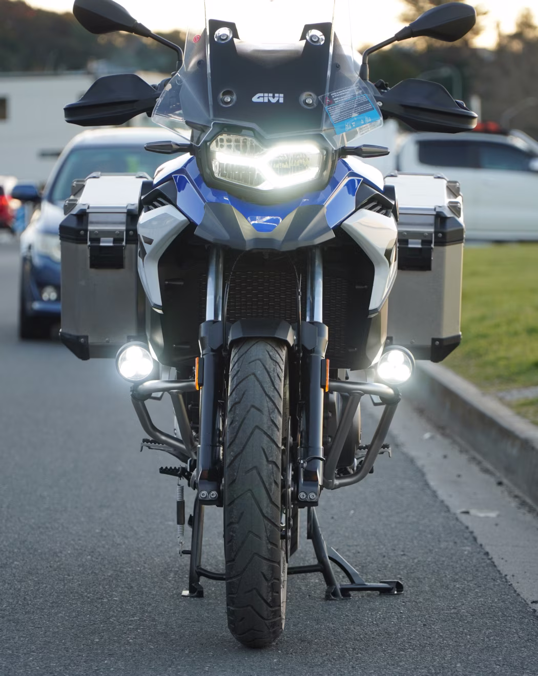 Front view of the BMW F800 GS with headlight and auxiliary driving lights on, GIVI touring screen, hand guards, crash bars and aluminium panniers