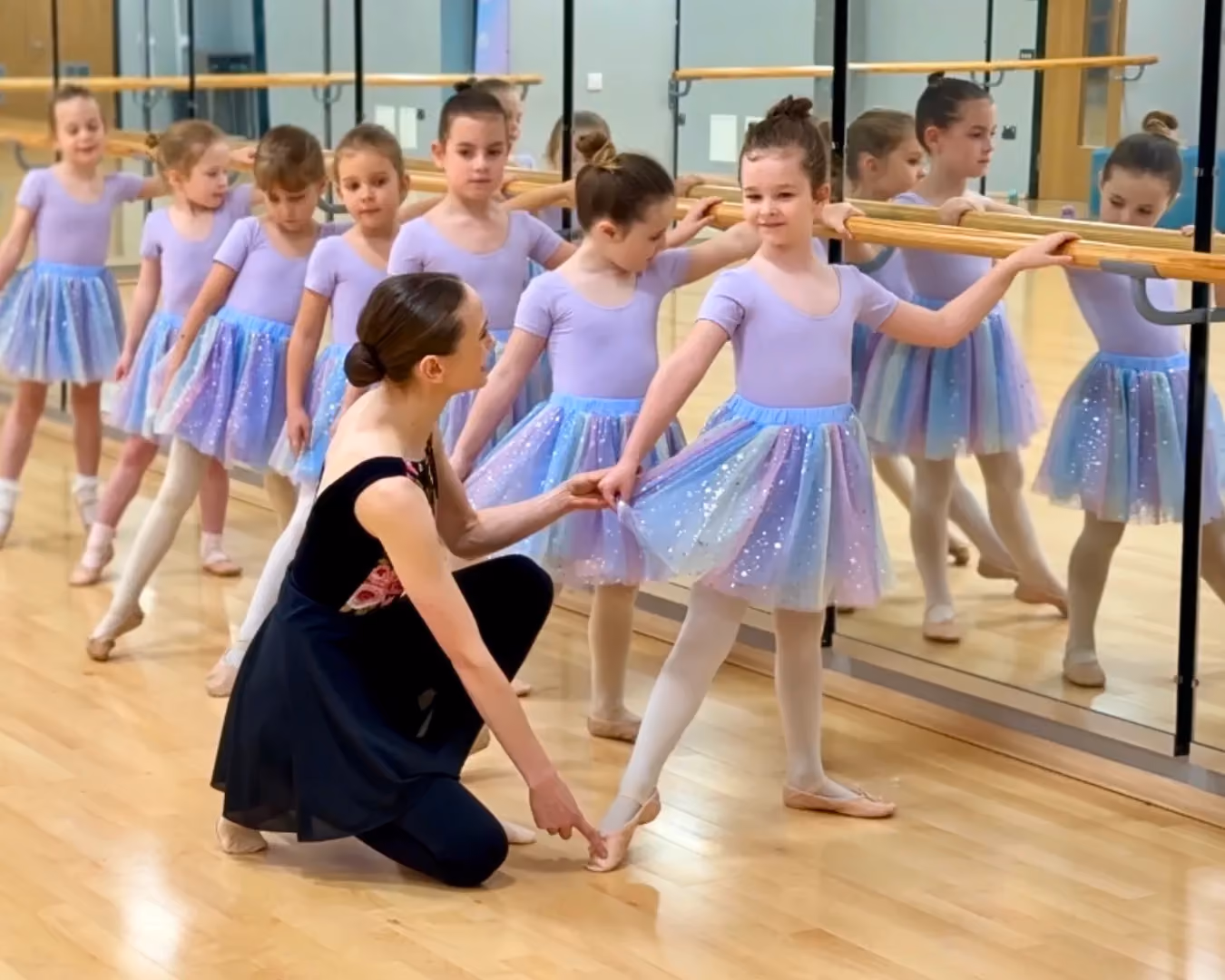 A teacher helping a child at their first ballet class near Northstowe