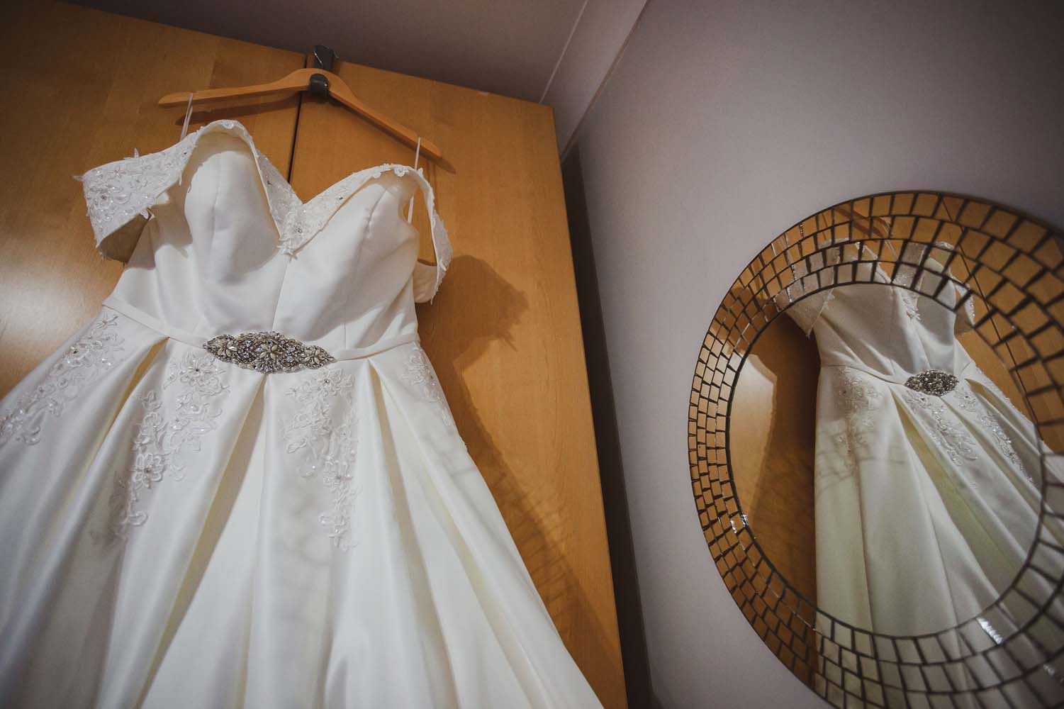 A Brides wedding dress haning on the wardrobe ready to wear.