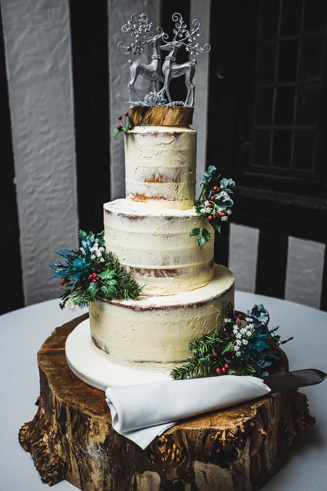 3 tier wedding cake with semi nude decoration and silver stags on the top.