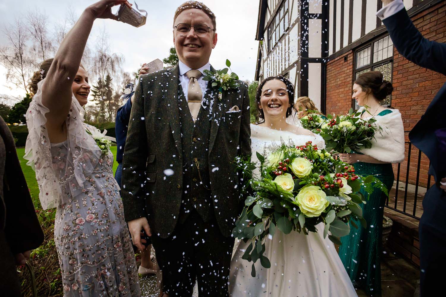 A Bride and Groom walking through their guests having confetti scattered over them.