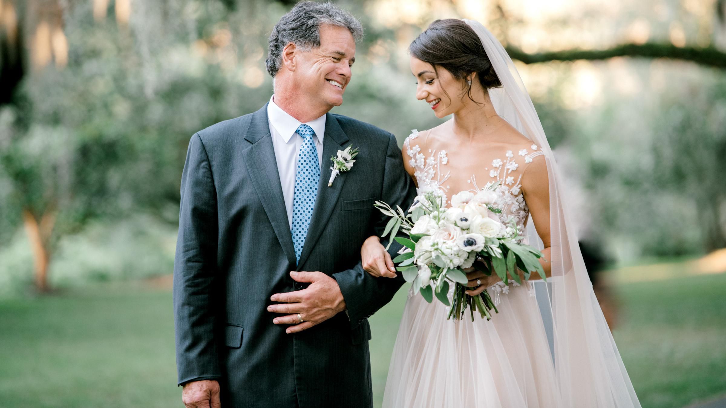 A Bride and her Father smiling at each other on her wedding day.