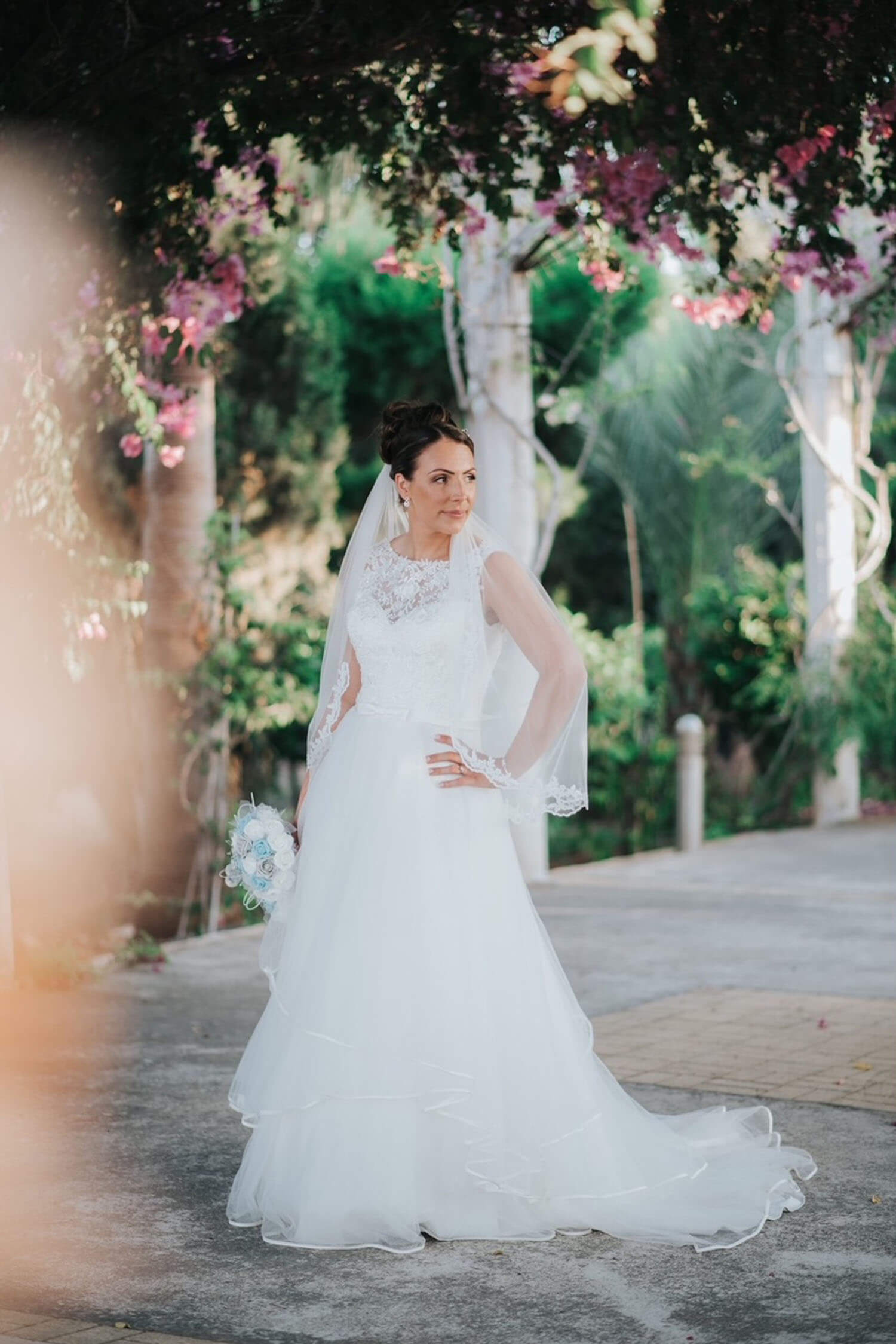 Bride wearing an ivory wedding dress with lace illusion neckline and satin edged tulle tiered skirt