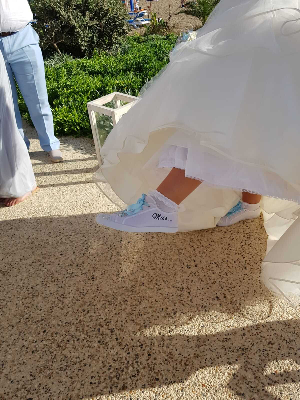 Bride showing off her customised wedding pumps with her name date and blue ribbon ties.