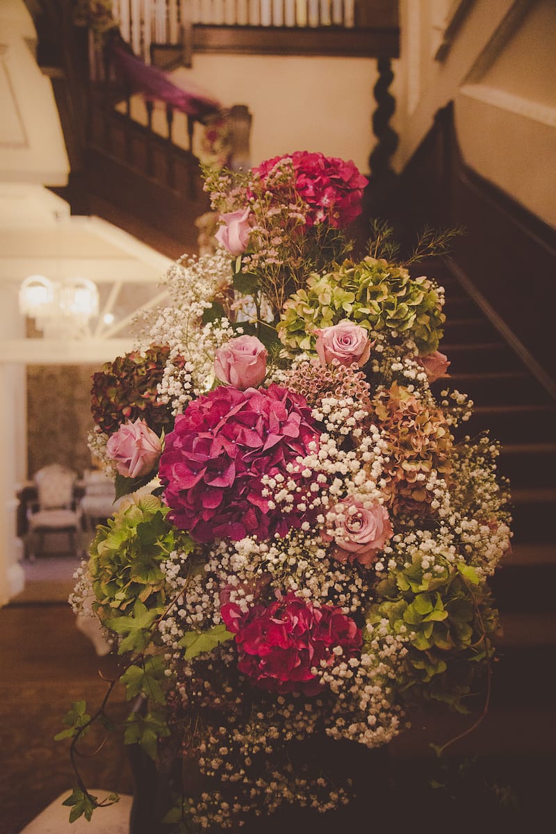 A Staircase decorated with burgundy and pink floral decorations Ready for a wedding ceremony..