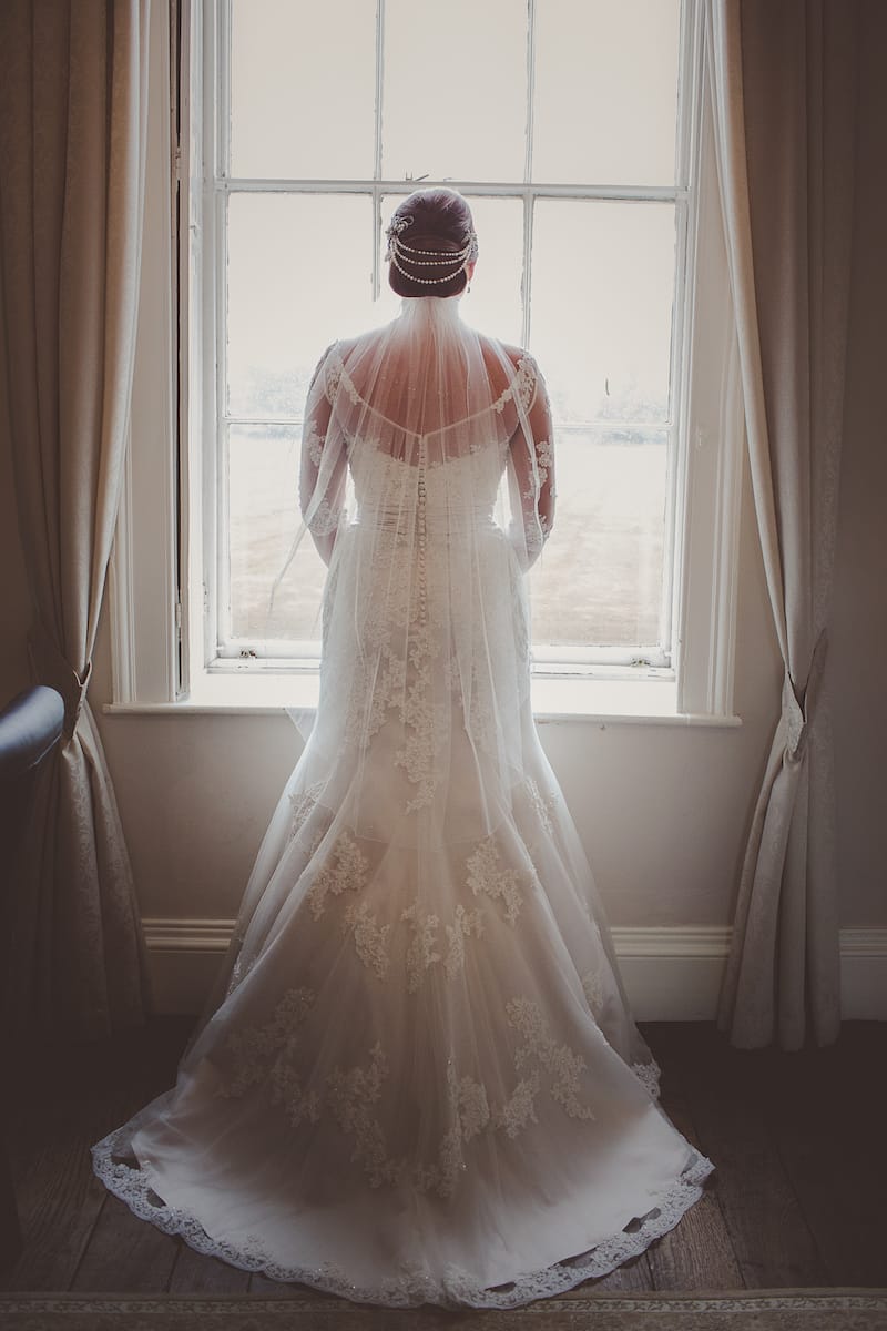 Bride ready for her ceremony, wearing an oyster coloured gown with hip length veil