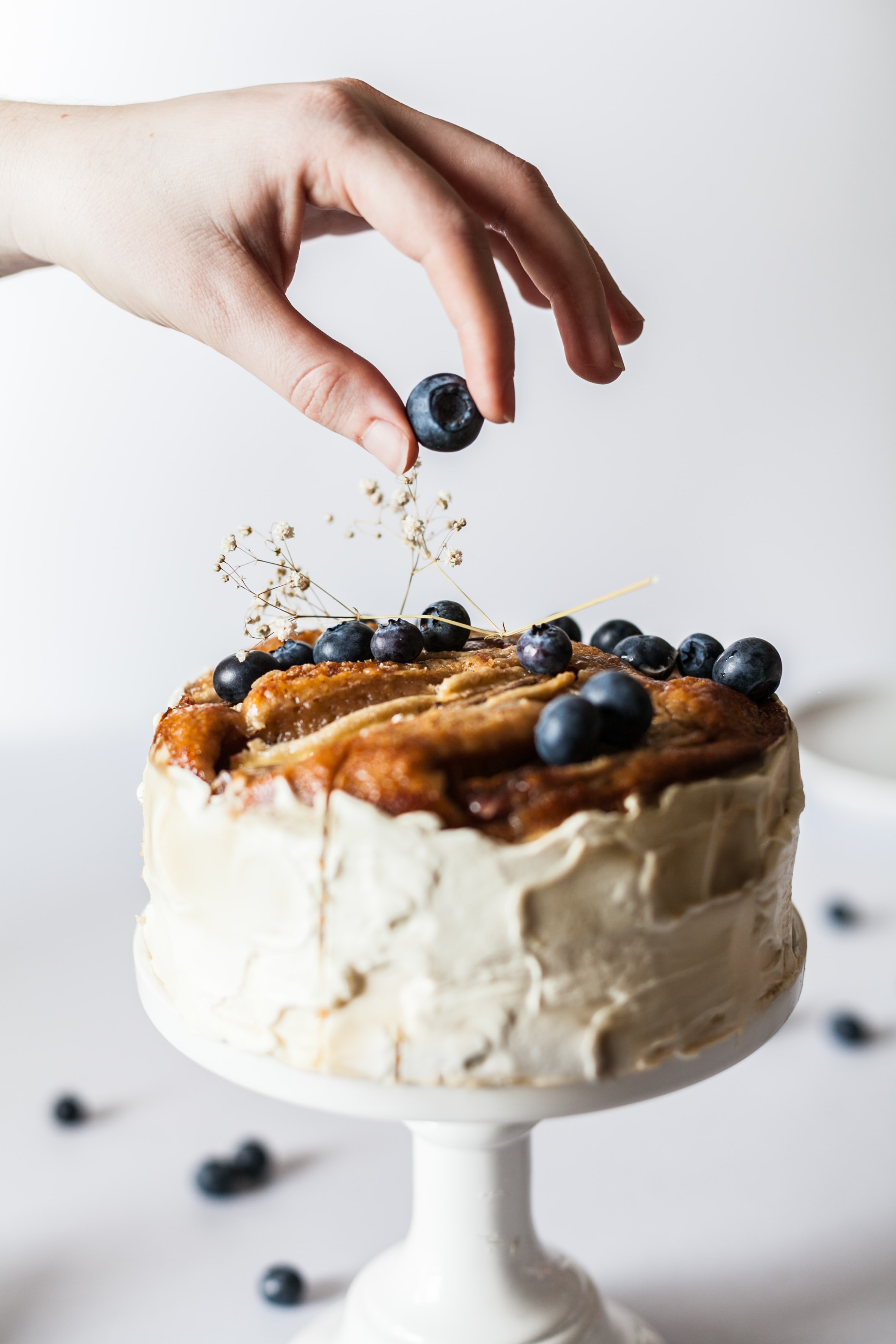 lady decorating a homemade cake with blueberries