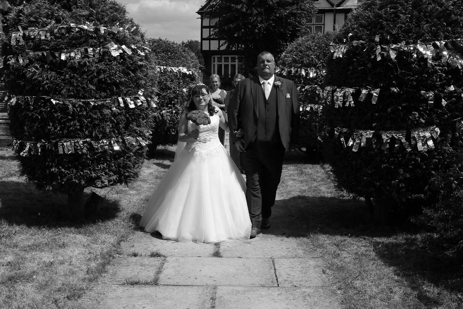 A bride leaving for the church on the arm of her father.
