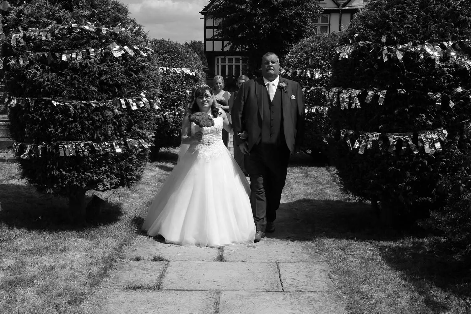 A bride leaving for the church on the arm of her father.