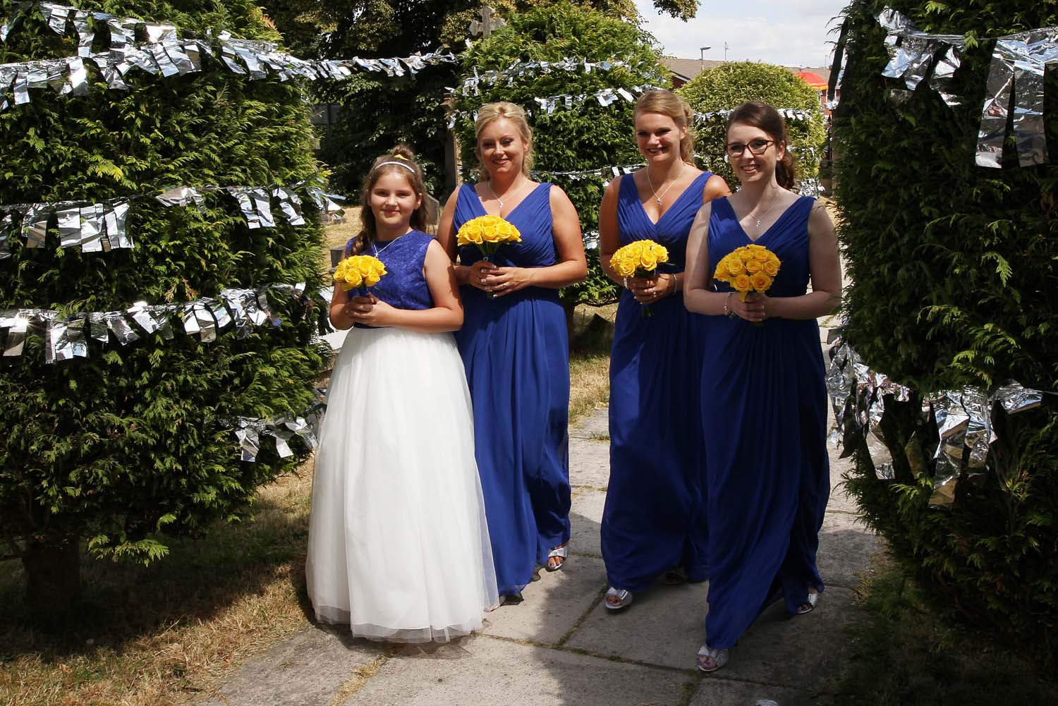 3 bridesmaids and a flower gil in royal blue dresses with lemon posies.
