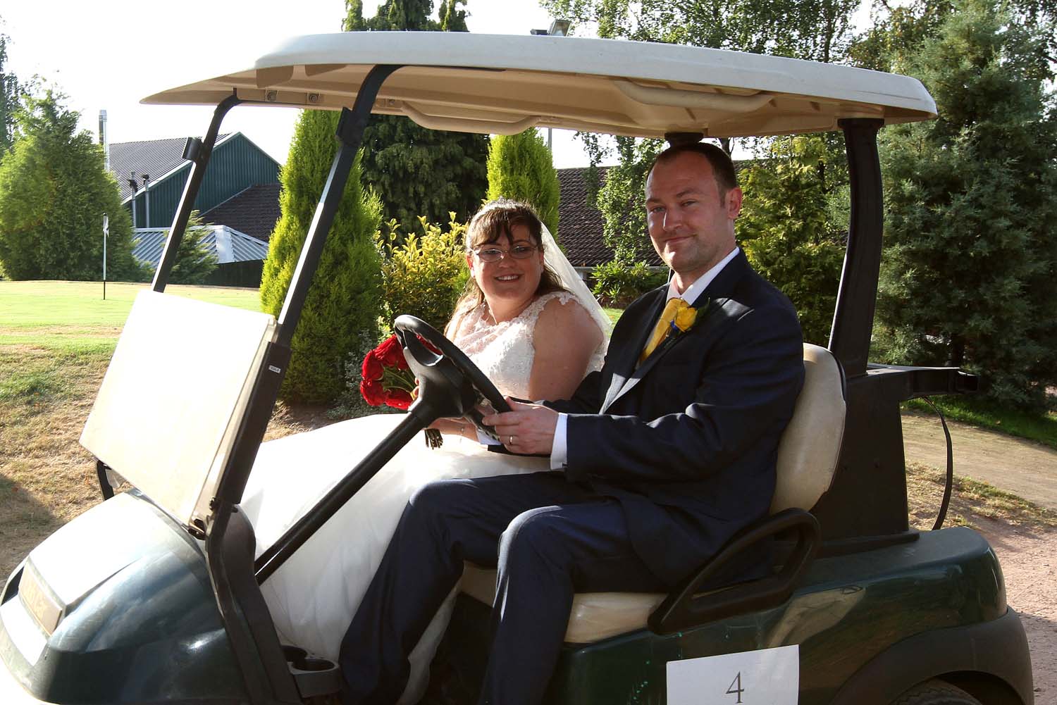 Bride and Groom taking a ride in a golf buggy.