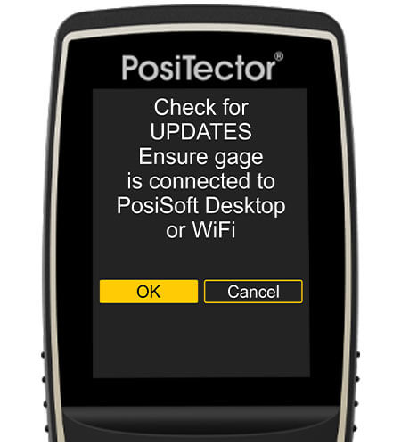 PosiTectorゲージ本体の画像、画面には「Check for UPDATES, Ensure gage is connected to PosiSoft Desktop or wifi」と表示され「OK」ボタンが選択される