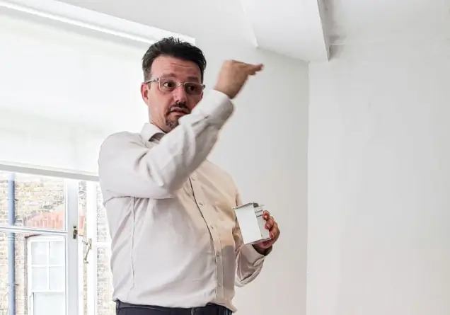 Man in glasses and white shirt installing or demonstrating a concealed window blind.