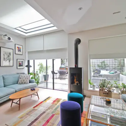 Modern building with large glass windows showing a minimalist interior with sofas and artwork.