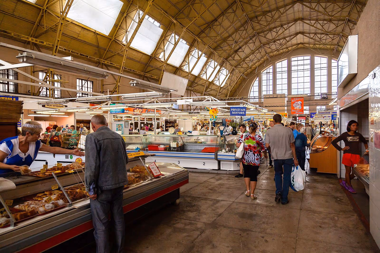 Shoppers walking and interacting with vendors at an indoor market.