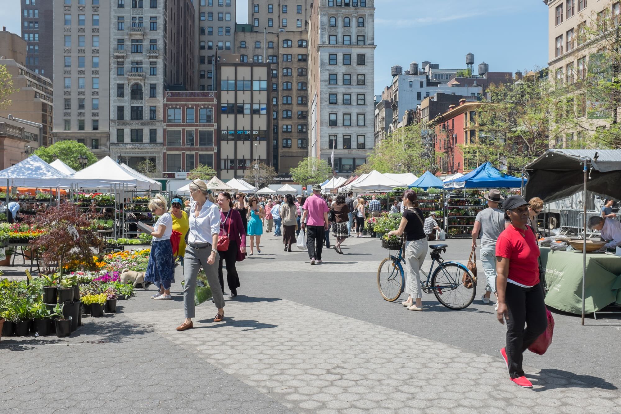 A busy outdoor farmers market on a sunny day