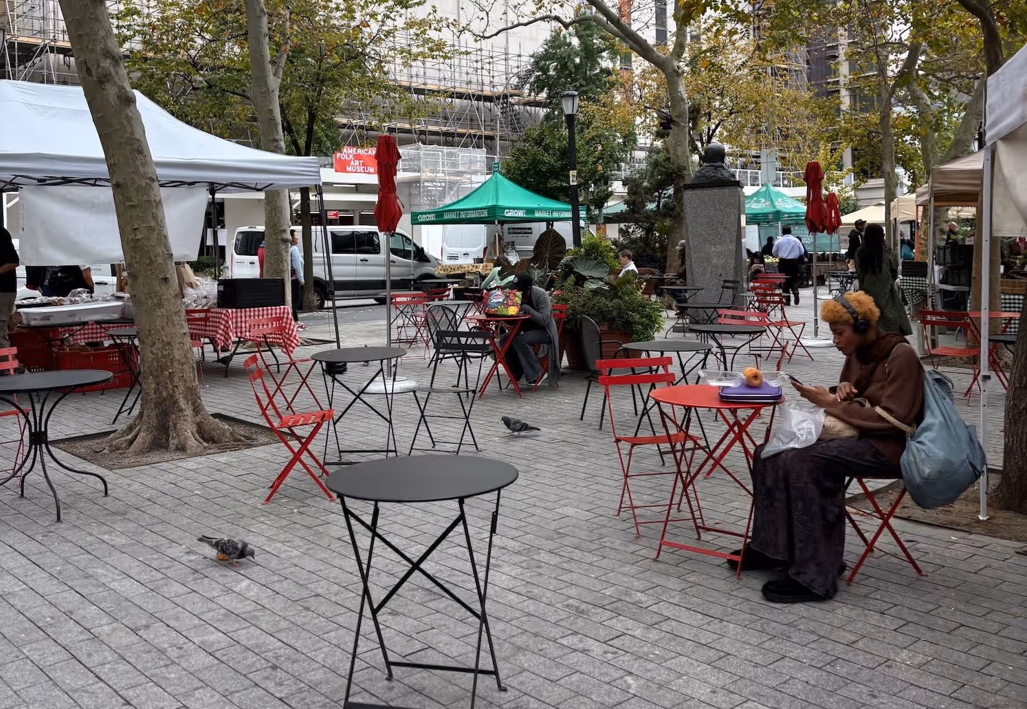 People are sitting on chairs that are set up near an outdoor farmers market