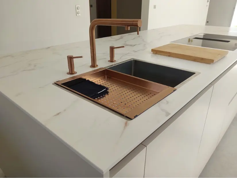 Détails plan de travail en marbre avec évier en cuivre, et espace minimaliste avec plaque de cuisson avec hotte aspirante intégrée à la plaque