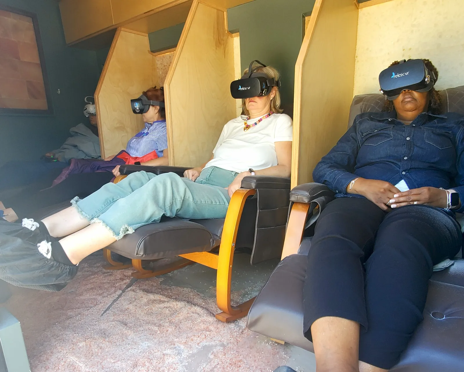 Clients relaxing in massage chairs wearing Relax VR headsets inside the Mobile Saltworks van