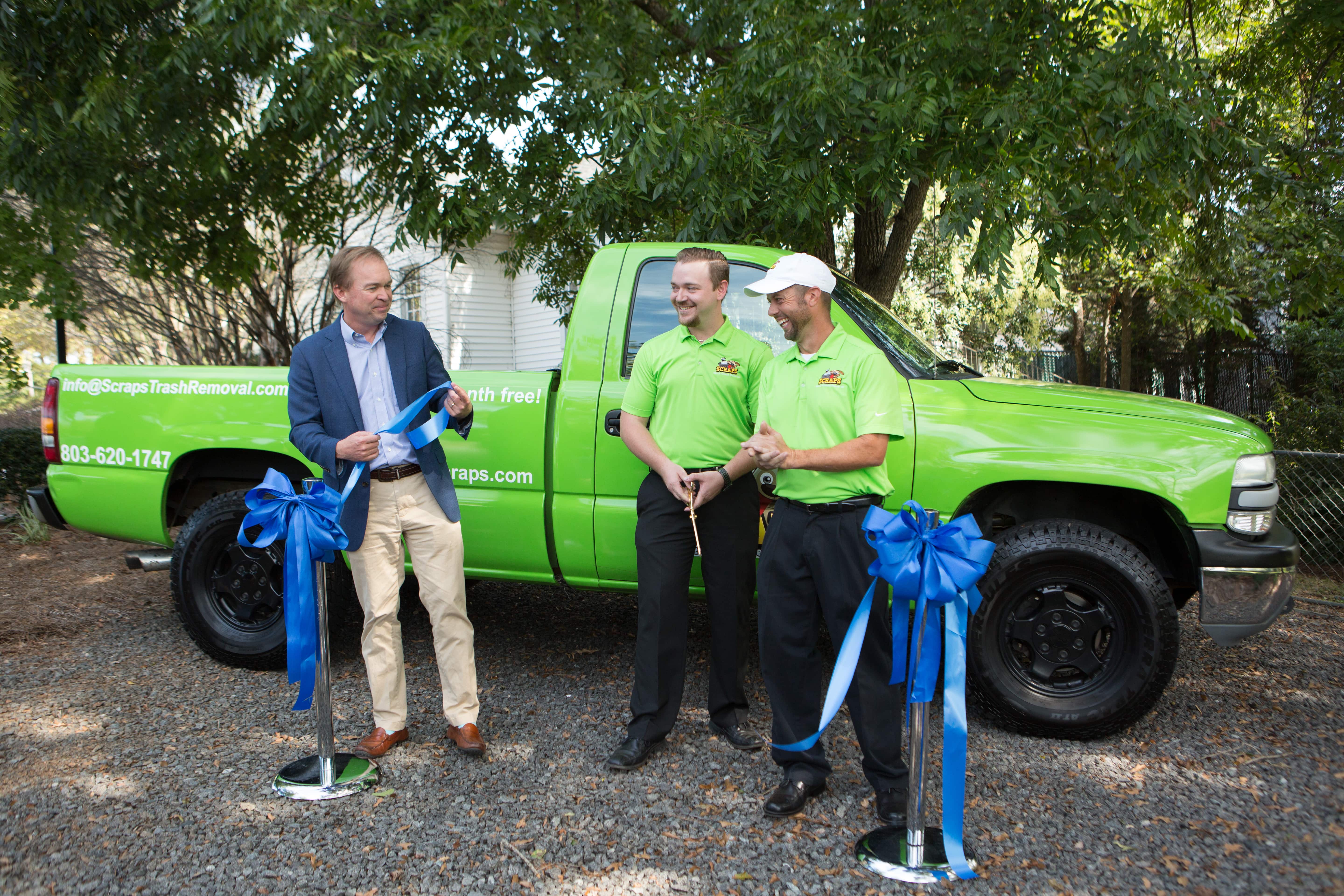 Ribbon-cutting moment with Scraps founders and Congressman Mick Mulvaney in front of branded green truck.